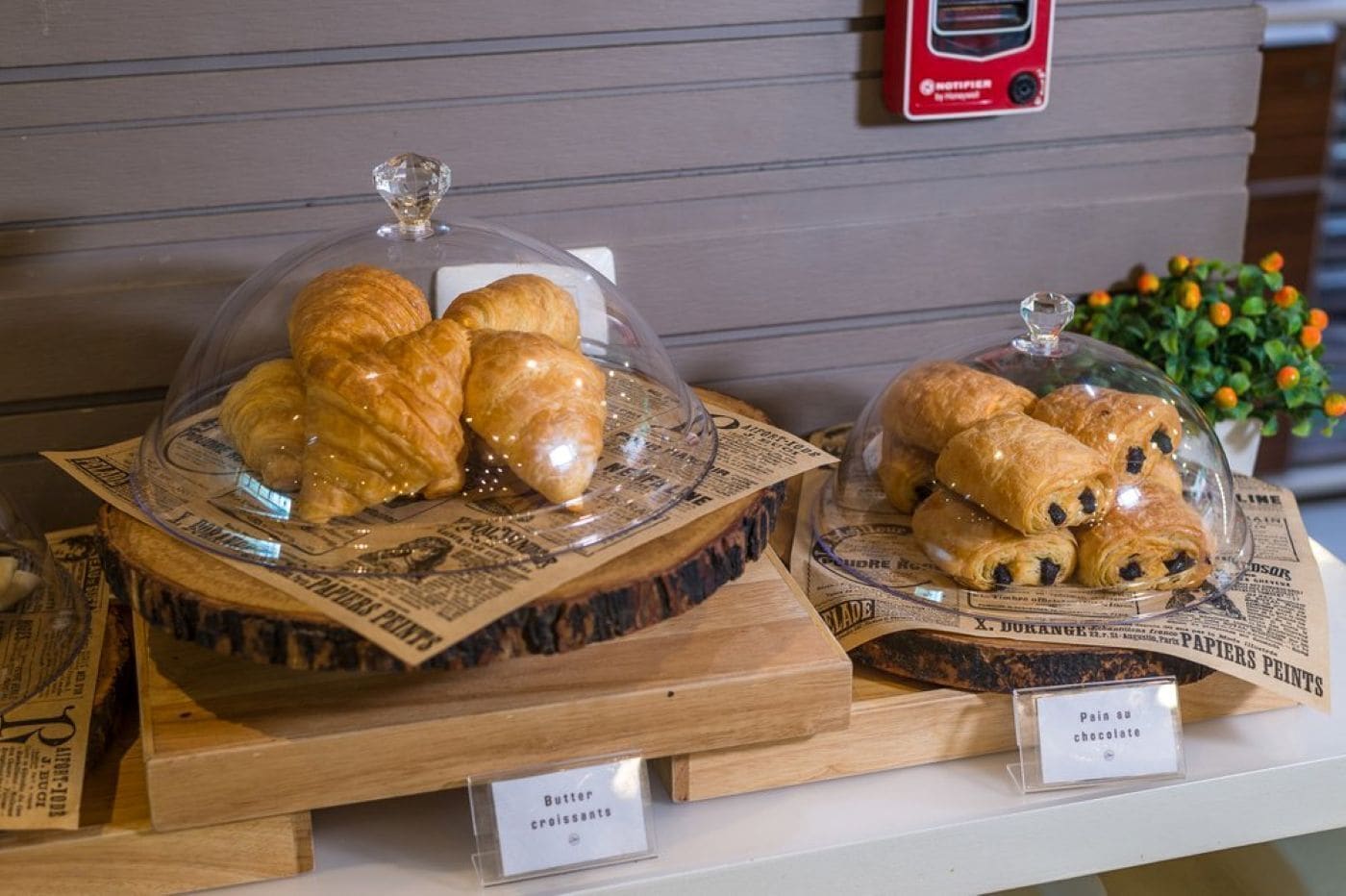 Exhibición de pastelería con dos secciones: una con croissants de mantequilla y la otra con panes de chocolate.