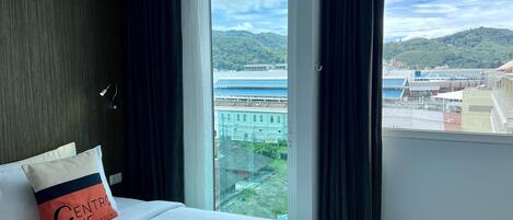 Une chambre d’hôtel avec un grand lit, une vue sur la côte et un paysage urbain en arrière-plan.