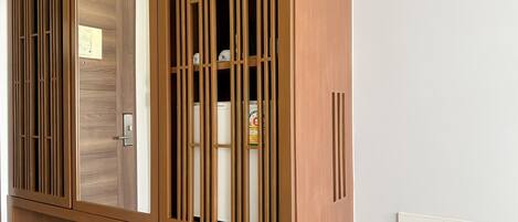 A wooden wardrobe with a mirrored door and vertical slats.