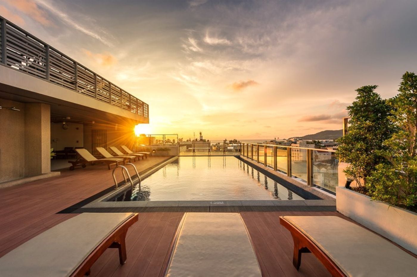 Une piscine sur le toit, dotée de chaises longues et offrant une vue sur le coucher du soleil.