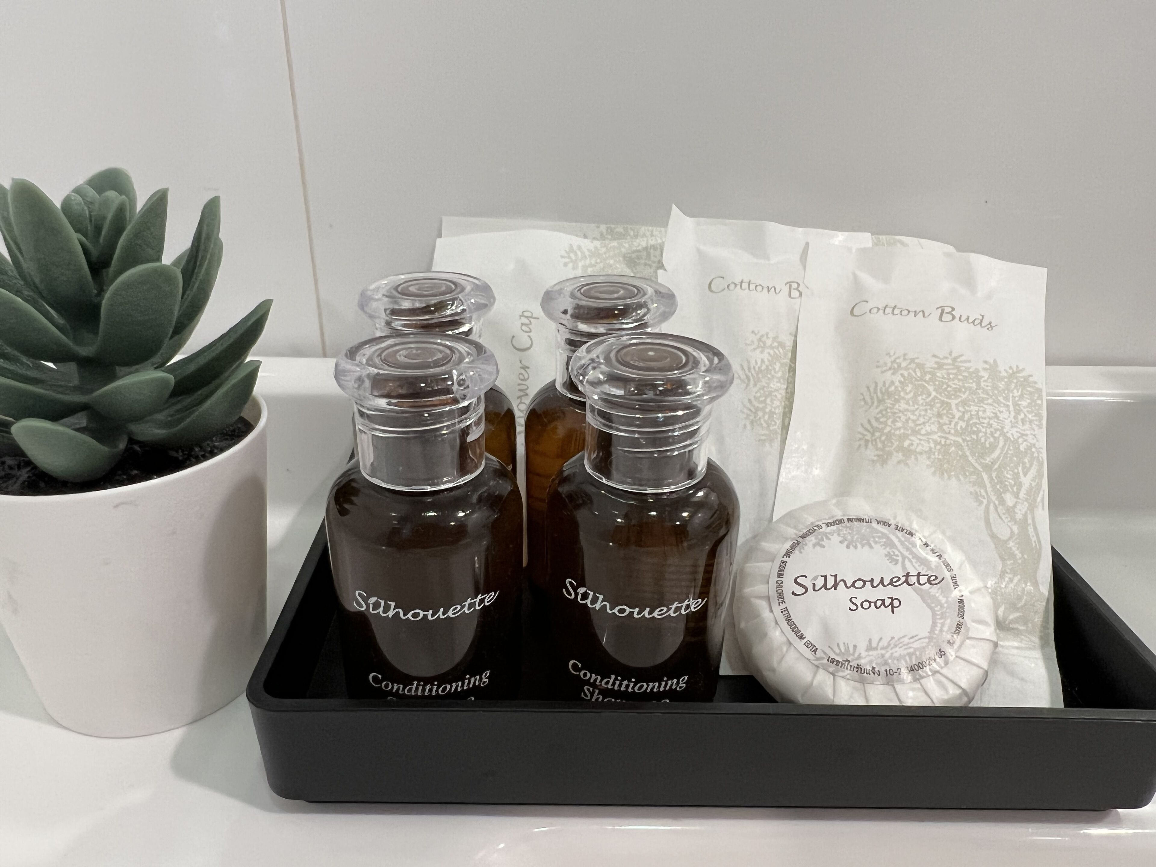 A tray with four bottles of 'Silhouette Soap' and a bag labeled 'Cotton Buds' on a white surface.