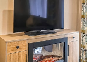 A television on a wooden cabinet with a built-in fireplace.
