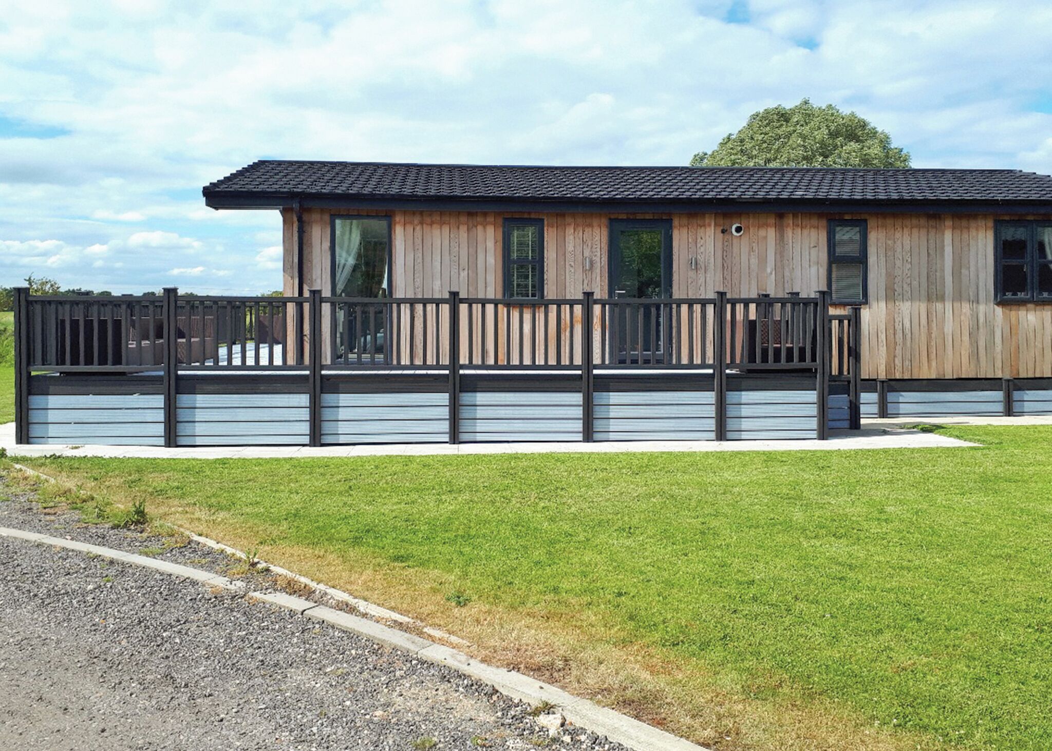 A modern building with a wooden facade, large windows, and a metal fence.