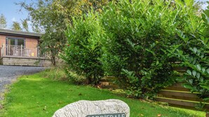 En skulptur föreställande ett får, huggen i sten, med en skylt som visar texten ”CORRIDALE”. Skulpturen står på en gräsyta med ett staket av trä och grönska i bakgrunden.