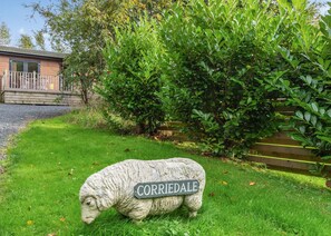 A stone sheep sculpture with a sign reading 'CORRIDALE' in a grassy area with a wooden fence and greenery in the background. - 1 bedroom accommodation in Cartmel (Cartmel)