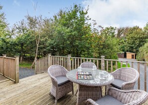 A deck with wicker furniture and a small shed in the background.
