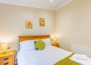 A neatly made bed with white linens, a wooden headboard, and two bedside lamps. - 1 bedroom accommodation in Cartmel (Cartmel)
