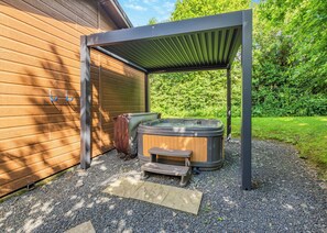A hot tub under a metal pergola next to a wooden building with a gravel path. - 2 bedroom accommodation in Cartmel (Cartmel)