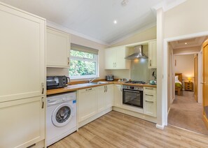 A compact kitchen with a washing machine, a microwave, a stove, and a sink. - 1 bedroom accommodation in Cartmel (Cartmel)