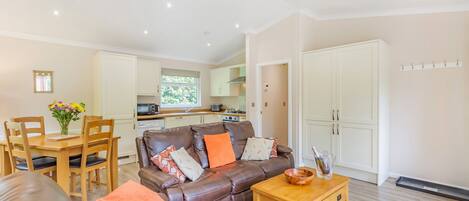 A modern living room with a leather sofa, wooden coffee table, and a dining area with a table and chairs.
