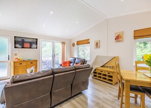 Un salon comprenant un canapé, une table à manger et un téléviseur fixé au mur.