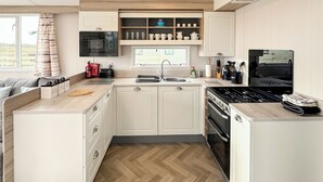 Eine kleine Küche mit weißen Schränken, einer Mikrowelle, einem Toaster, einem Spülbecken und einem Herd.