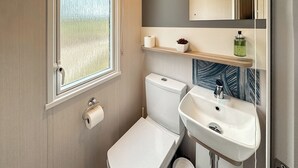 Ein kleines Badezimmer mit Toilette, Waschbecken und einem kleinen Mülleimer.