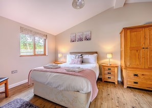 Un dormitorio con cama, mesitas de noche, armario y ventana.