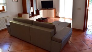 Una sala de estar con sofá, televisor, aparador y radiador.