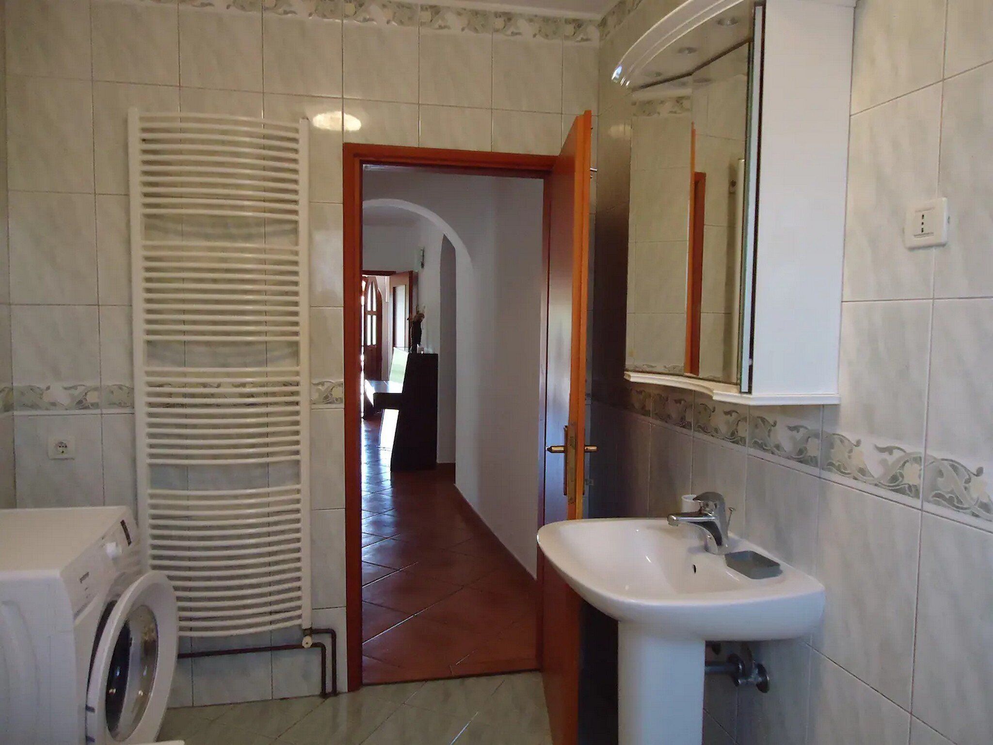 Une salle de bain équipée d’un lave-linge, d’un lavabo et d’un miroir.