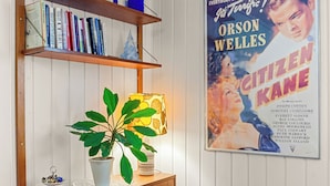 A room with a wooden cabinet, shelves with books, a potted plant, and a movie poster on the wall. - Krokenskogen (Sandefjord)