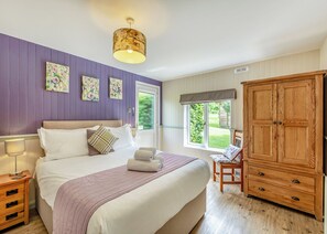 A bedroom with a bed, a wooden wardrobe, a window with a view, and a ceiling light fixture.