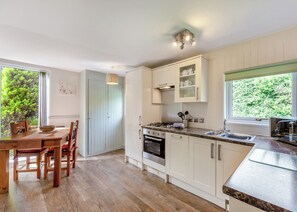 Une cuisine moderne avec un coin repas, un plancher en bois et une vue sur la verdure environnante.