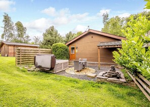 A wooden cabin with a patio, a covered seating area, and a stone fire pit. - 1 bedroom accommodation in Cartmel (Cartmel)