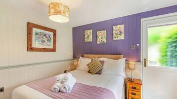 A bedroom with a bed, a bedside table, a lamp, and a door with a view.