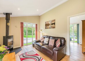 A living room with a fireplace, a leather sofa, a rug, and a painting on the wall.