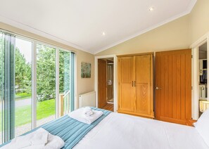 A bedroom with a bed, a large window, a wardrobe, and a radiator.