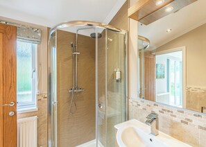 A modern bathroom with a glass-enclosed shower, a white sink, and a large mirror.