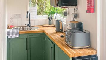 A compact kitchen with a sink, a toaster, a kettle, and a microwave.