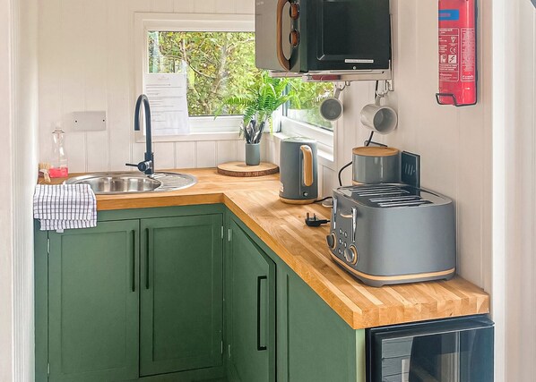 A compact kitchen with a sink, a toaster, a kettle, and a microwave. - Brand new for 2021 is this stunning open plan modern hotel suite lodge. (Moortown)