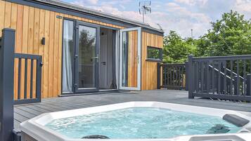 Une construction en bois dotée de portes vitrées, d’un jacuzzi et d’une terrasse.