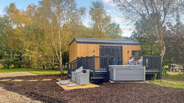 Eine kleine Holzhütte mit einer Terrasse, einer Feuerstelle und Sitzgelegenheiten im Freien.