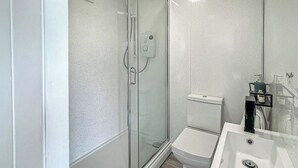 Une salle de bain avec une douche à parois de verre, des toilettes et un lavabo.