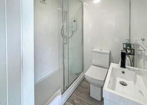A bathroom with a glass shower enclosure, a toilet, and a sink.