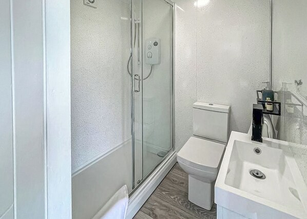 Ein Badezimmer mit Duschkabine, Toilette und Waschbecken.