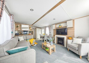 A modern living room with a sofa, chairs, a coffee table, a fireplace, and a TV.