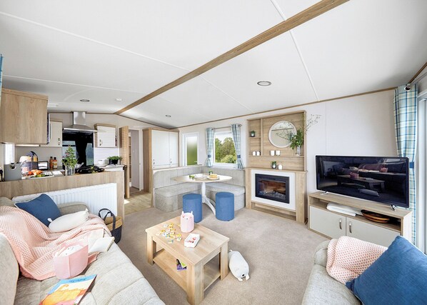 Un espacio habitable compacto con kitchenette, zona de estar y televisor.