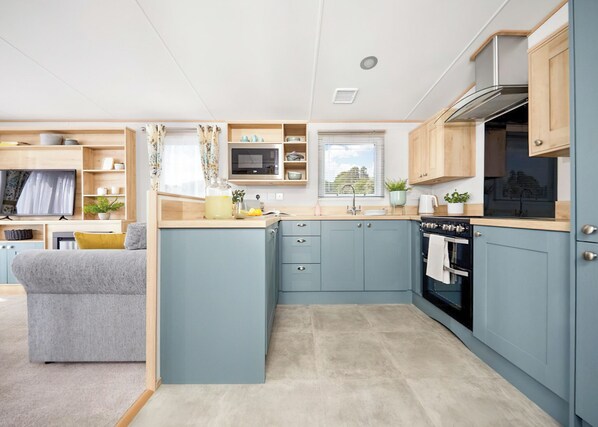 A modern kitchen with blue cabinets, a built-in oven, and a microwave.