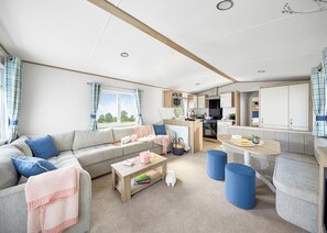 A modern, well-lit living area with a sofa, coffee table, and a dining table.