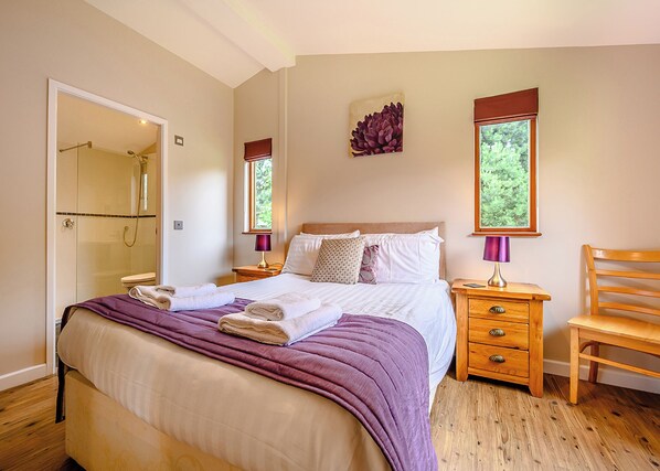 Une chambre à coucher comprenant un lit, des tables de chevet, une chaise, une fenêtre et un espace douche.