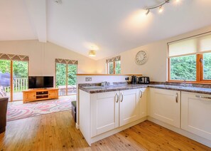 A modern kitchen with white cabinets, a built-in oven, and a large window.