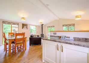 Une cuisine avec un plancher en bois, des armoires blanches, une table à manger avec des chaises et un four encastré.