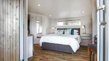 A bedroom with a bed, bedside tables, a window, and a wooden floor.