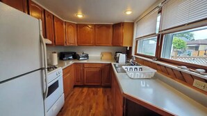 A compact kitchen with wooden cabinets, a white refrigerator, a microwave, a toaster, and a sink. - 3-bedroom vacation home just a short walk to Lake Michigan (Racine)