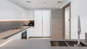 Una cocina moderna con encimera de acero inoxidable, horno integrado y puerta de madera.