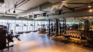 Un gimnasio con cintas de correr, máquinas de pesas y pesas libres.