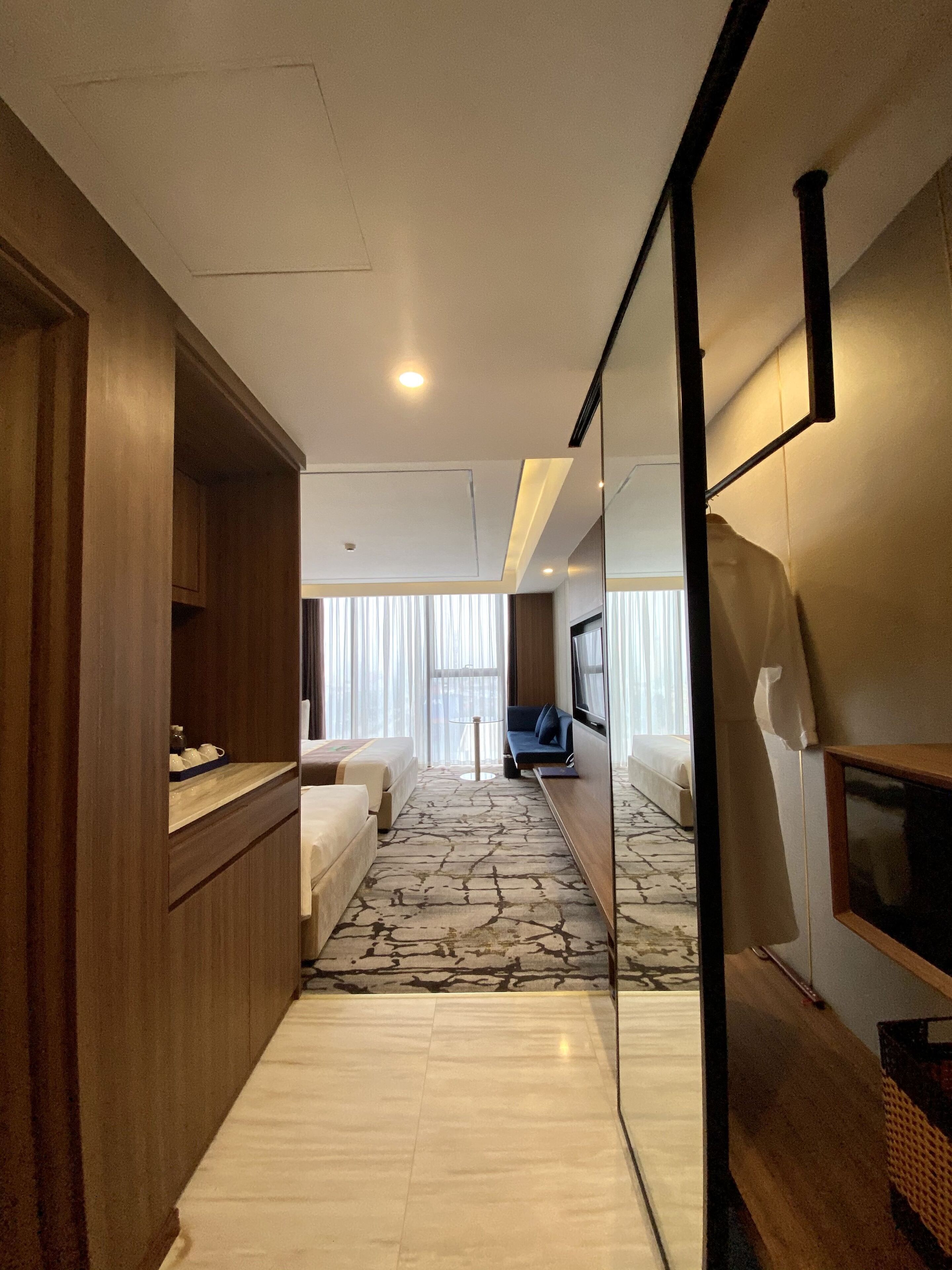 Een hotelgang met een modern ontwerp, met een houten kast, een bank, een televisie en een kamerbreed tapijt.