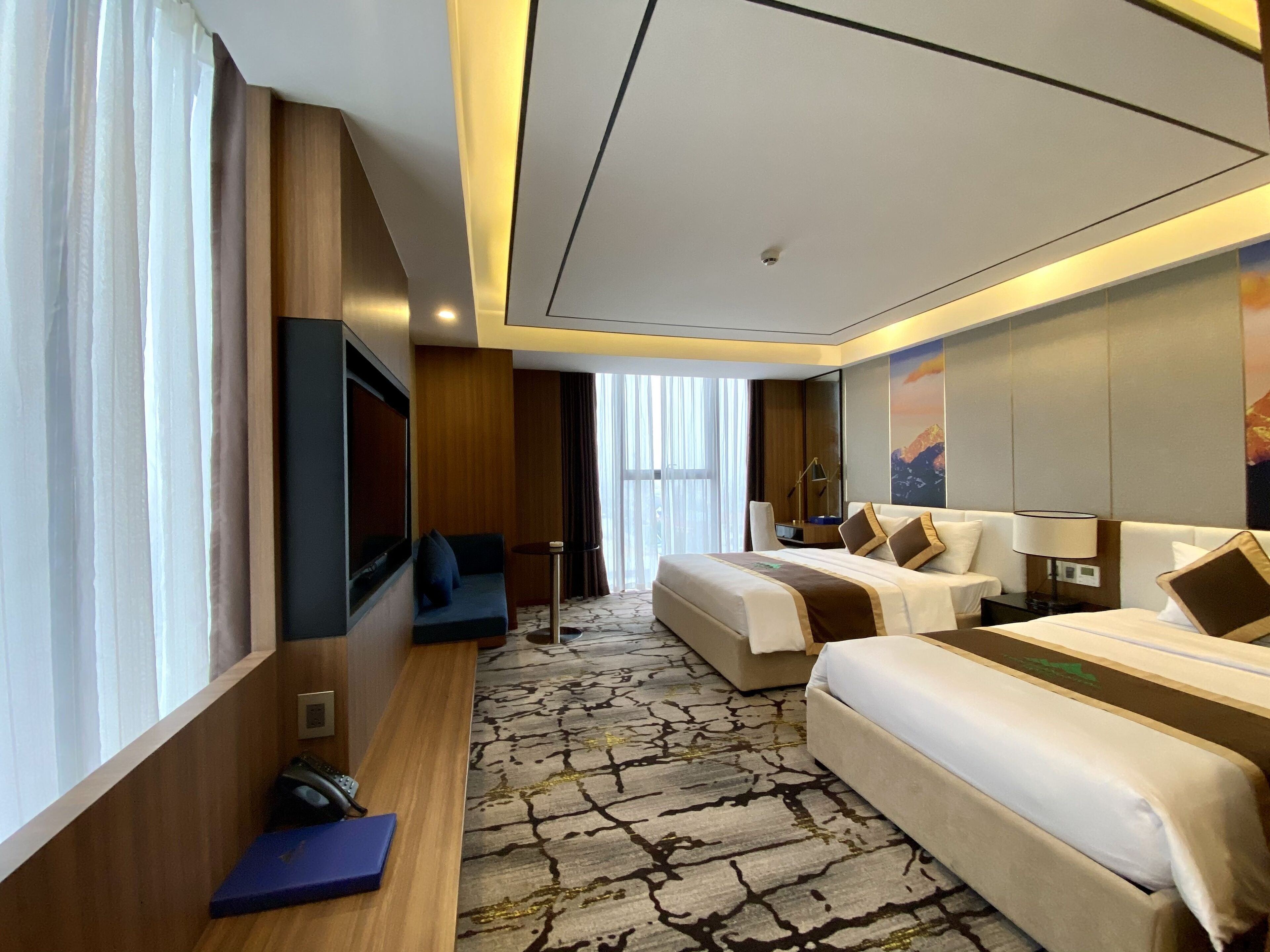 A hotel room with a large bed, a sofa, a TV, and a desk.
