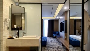 Un baño de hotel moderno con un espejo grande, un lavabo y un banco.