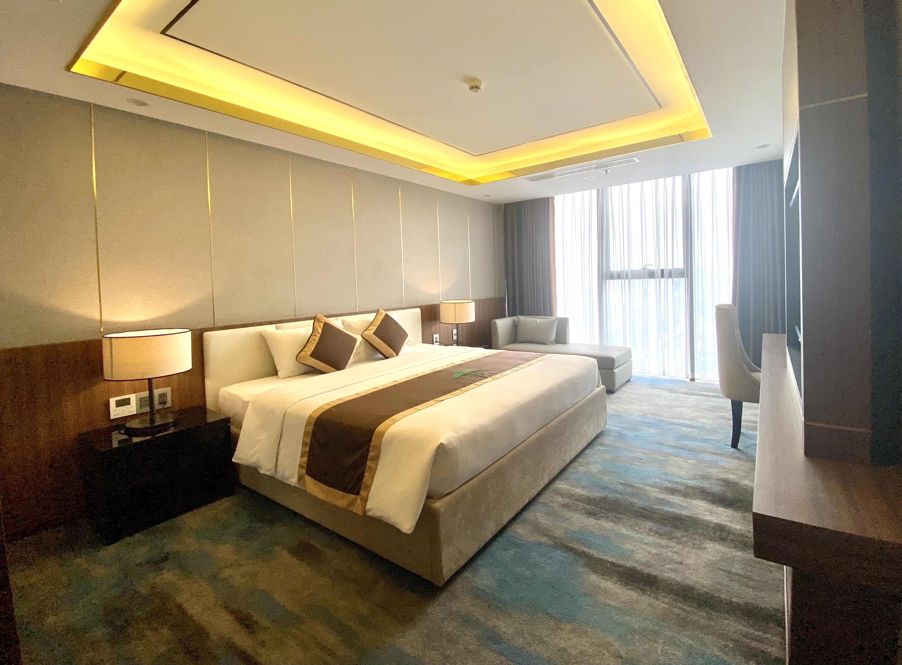 A hotel room with a large bed, bedside tables, a desk, and a chair.
